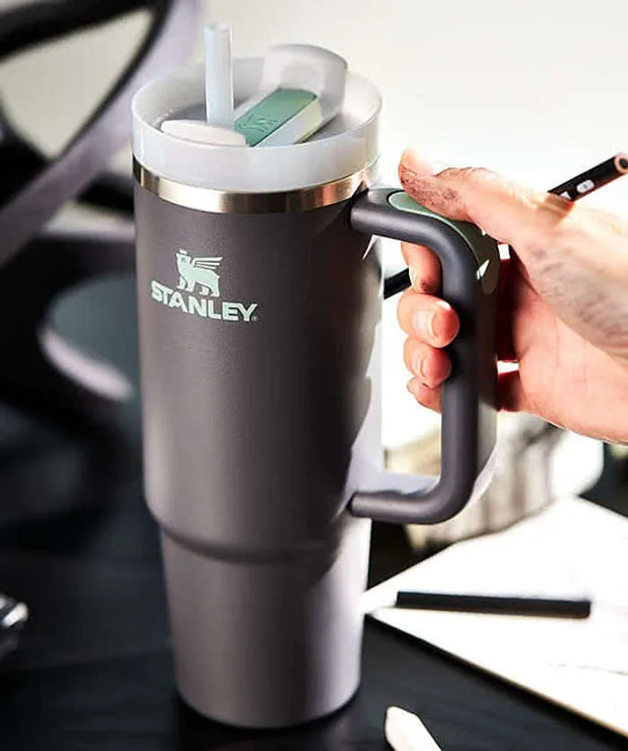 Stanley insulated tumbler with handle being held in a car, designed for hydration on the go