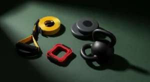 Core stability training equipment including TRX suspension trainer, gliding discs, resistance band, and kettlebell on a dark green surface
